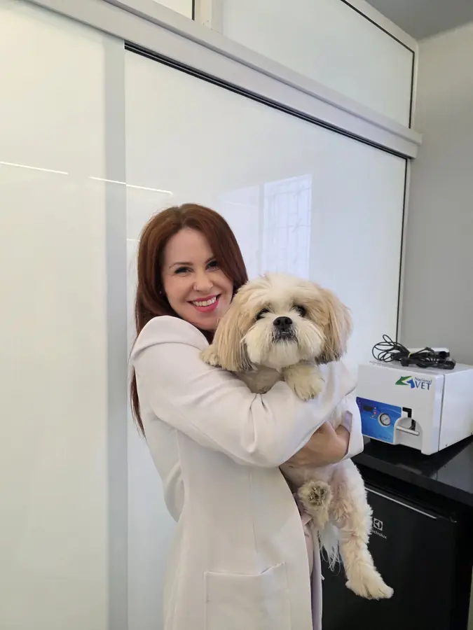 Dra. Clarice segurando um cão durante a consulta